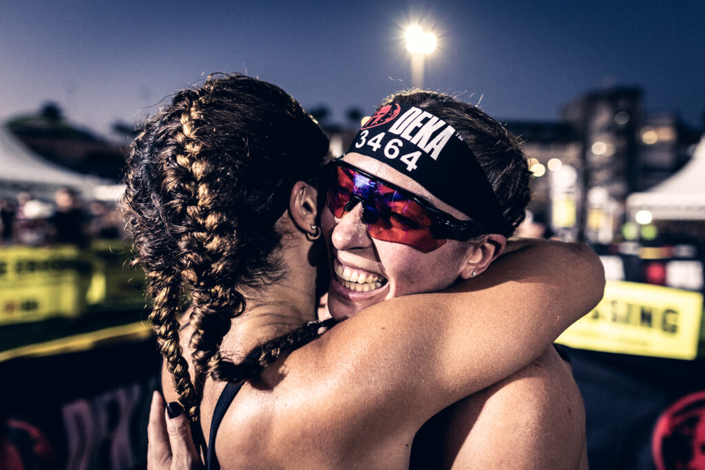Two DEKA Middle East competitors embracing after completing a functional fitness race, highlighting achievement and community spirit.