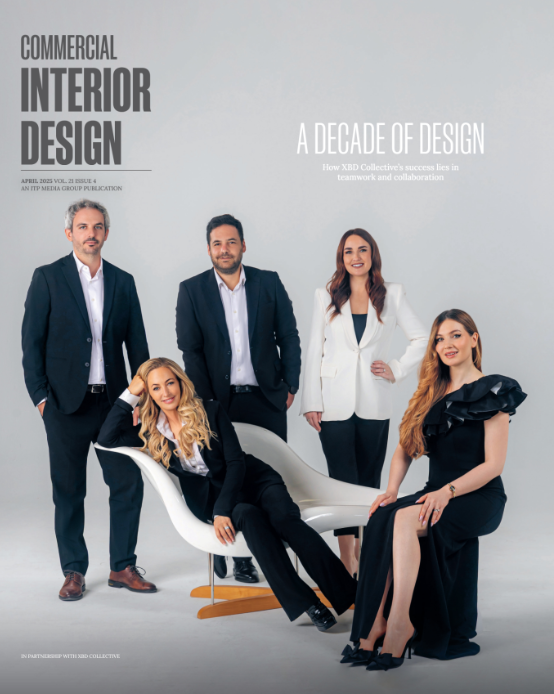 A magazine cover featuring five professionally dressed individuals standing and sitting together in a studio setting, posing confidently.