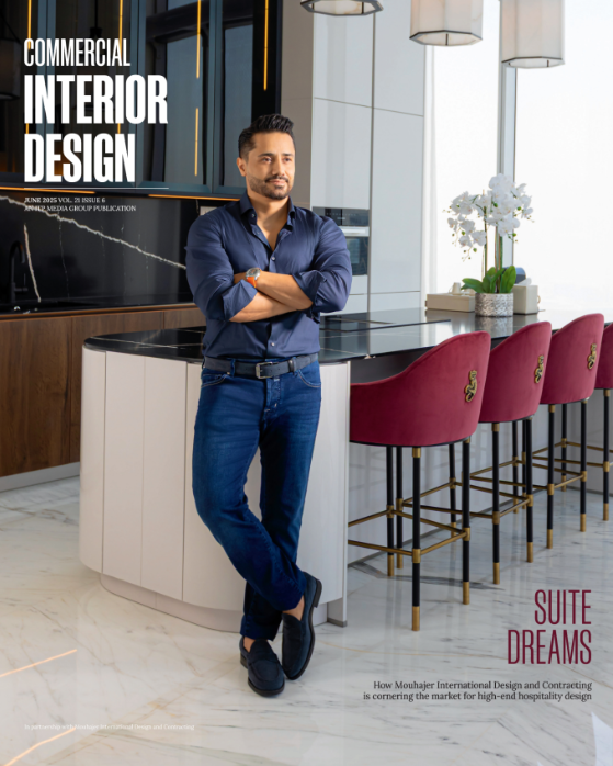 A magazine cover featuring a man standing with arms crossed inside a modern bar or hospitality space with high stools and a sleek counter.