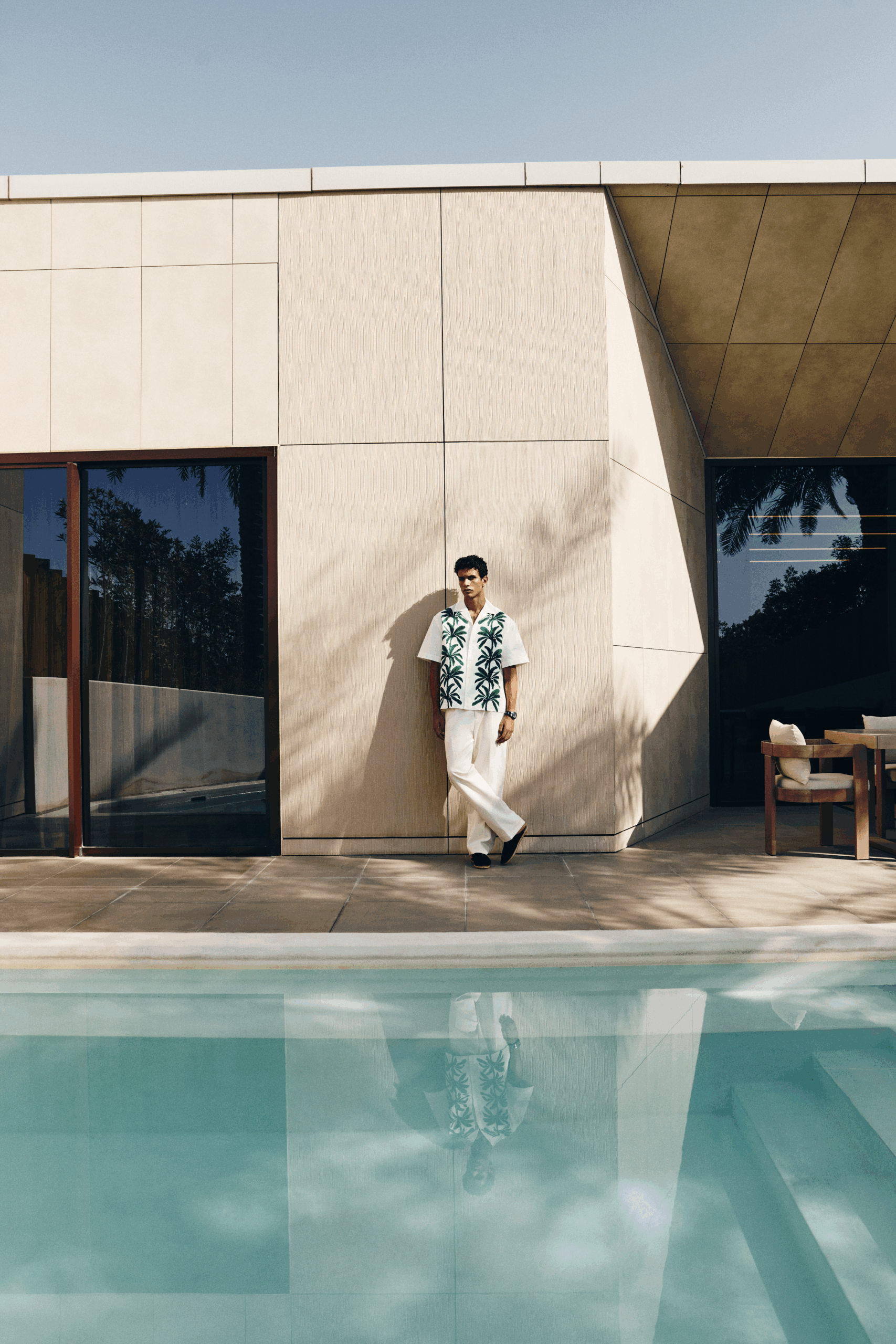 Male model standing beside a modern luxury villa and swimming pool in a minimalist architectural setting for Esquire Middle East fashion editorial.