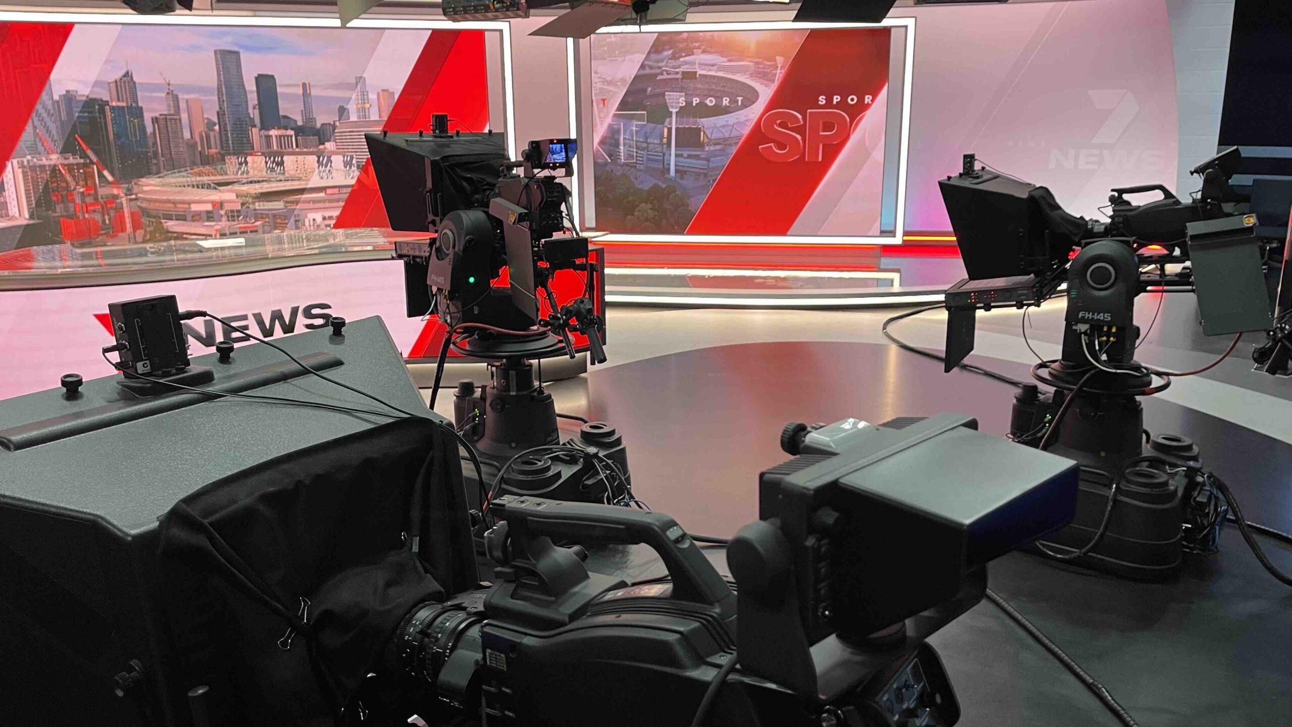 Professional broadcast cameras positioned inside a modern television news studio with large digital screens representing Digital Studio India production technology.