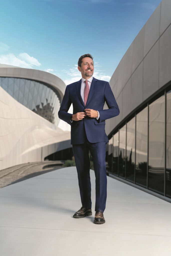 Business executive standing outside a modern commercial building representing Facilities Management Middle East digital industry coverage.