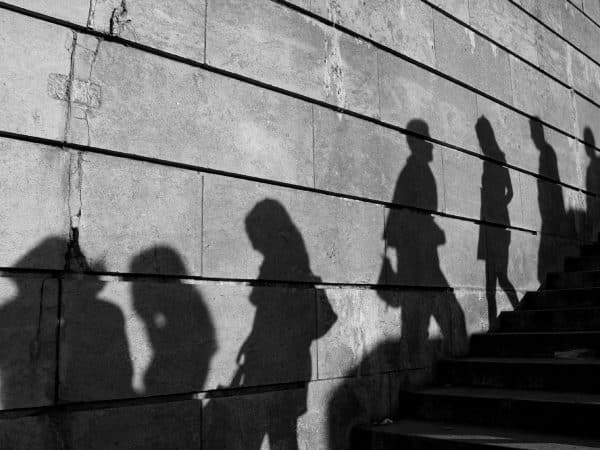 Silhouettes of people walking up a staircase against a textured concrete wall, representing dynamic movement and modern digital engagement.